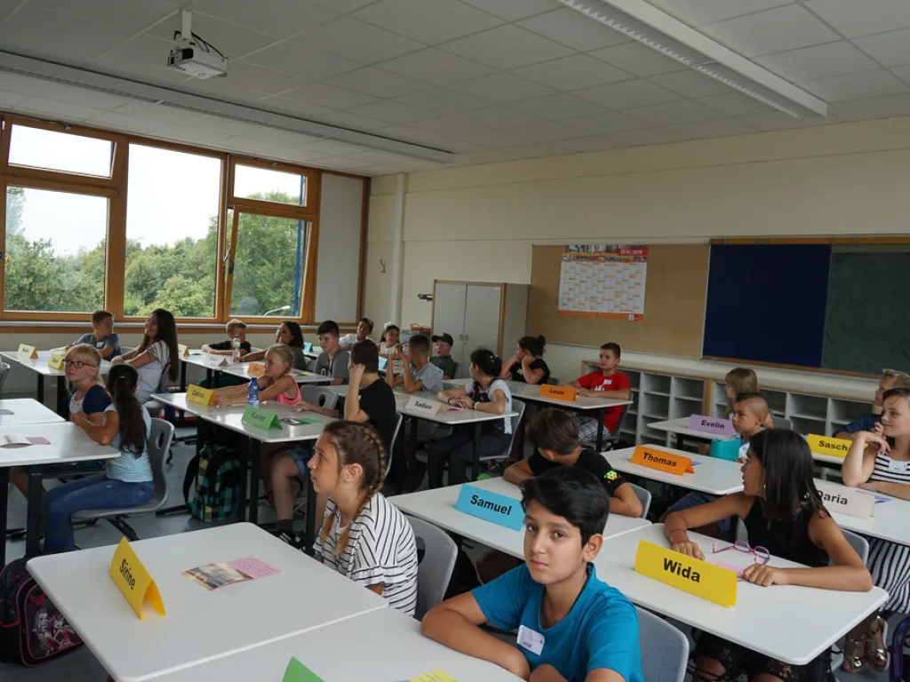 Kinder sitzen mit Namensschildern an ihren Tischen.